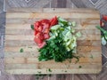 Sliced Ã¢â¬â¹Ã¢â¬â¹tomatoes, bell peppers, dill, parsley and cucumber on a wooden surface, top view. Fresh salad on a cutting board. Royalty Free Stock Photo